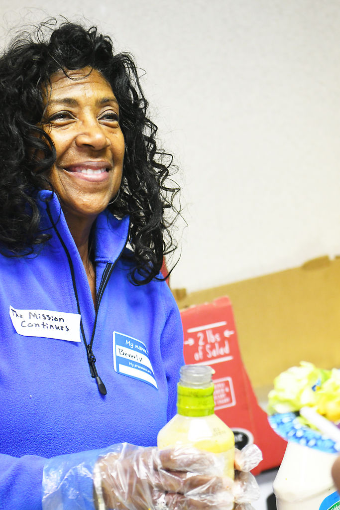 Beverly Green smiles at a client after pouring salad dressing during the Project Homeless Connect winter 2020 event